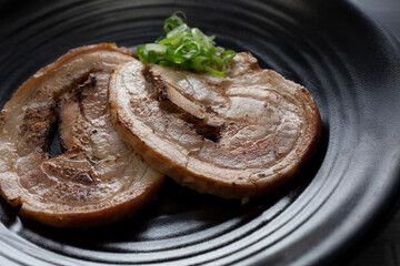 A view of slices of pork chashu on a plate.
