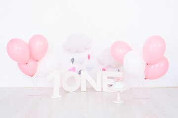 background decoration for first birthday celebration with cake, letters saying one and pink balloons.