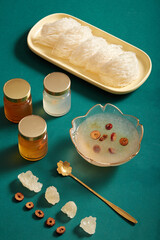 Bird’s nest on dishes, bowl soup, jujube, rock sugar and glass bottles without label on green background. Healthcare food, have effects: Anti-neurasthenia and increase the body's resistance