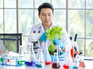 Asian professional male scientist researcher in white lab coat rubber gloves sitting using...