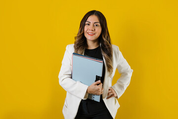 young hispanic business woman holding folders posing isolated over yellow background in Mexico Latin America