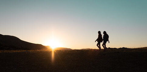 two people walk along a mountain range