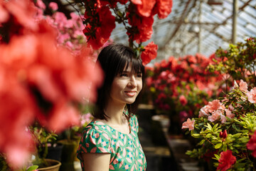 Beautiful girl in a green dress in a garden of blooming azaleas