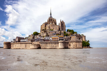 View of the beautiful cathedral Le Mont Saint-Michel in Normandy, France, at low tide, clay beach