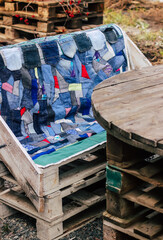 patchwork style denim bedspread on a wooden pallet chair near a wooden table, needlework and handicraft