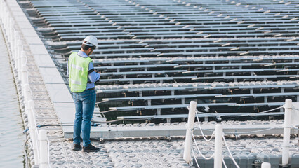 An young engineer is checking with tablet an operation of sun and cleanliness on field of photovoltaic solar panels on a sunset. Concept:renewable energy, technology,electricity,service, green,future