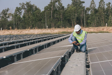 Engineer inspector holding laptop and working in solar panels power plant checking photovoltaic cells and electricity production.