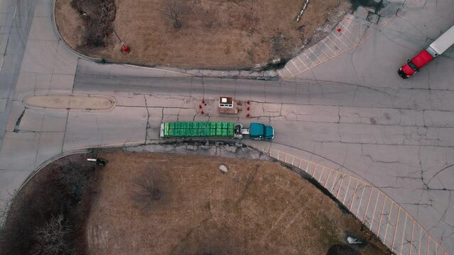 Flatbed Semi truck driver enters truck stop while red tractor with white trailer exits. In the middle security guard check. Aerial 4k USA