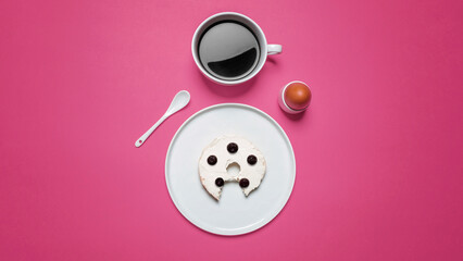 Overhead view of bun with egg and coffee on pink background