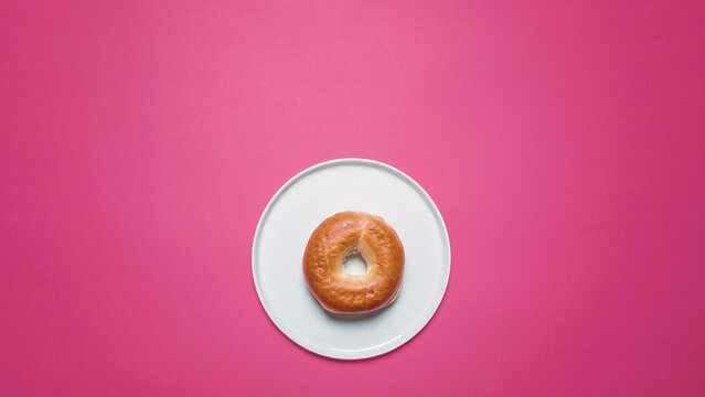 Overhead view of bun in plate on pink background