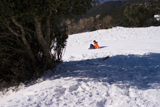 Playful boy sliding on ski slope during winter