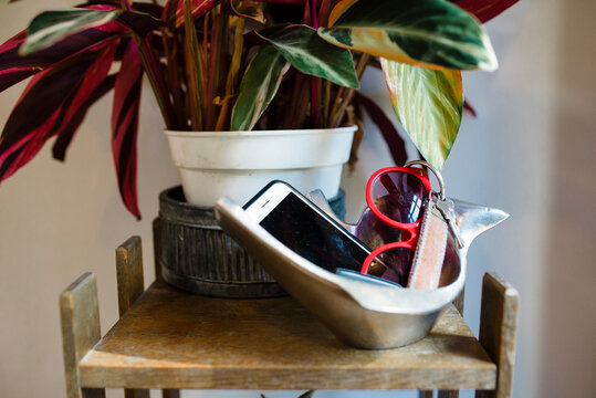 Close-up of sunglasses, smart phone and key in container by potted plant on table at home