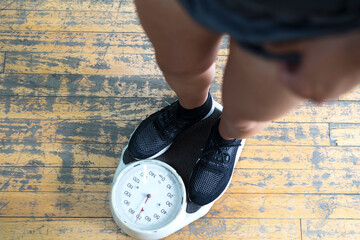Low section of man checking weight on scale in gym