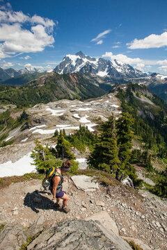 High angle view of female hiker climbing mountain against blue sky during sunny day