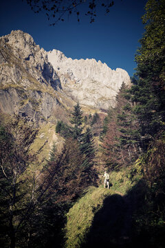 Low angle view of man hiking on mountain against clear blue sky during sunny day