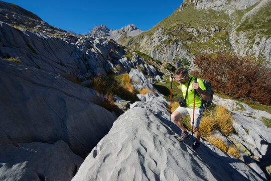 Male hiker with poles hiking on mountain during sunny day