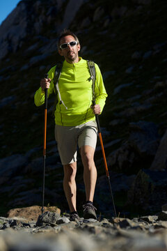 Surface level of man hiking on rocky field against mountain during sunny day