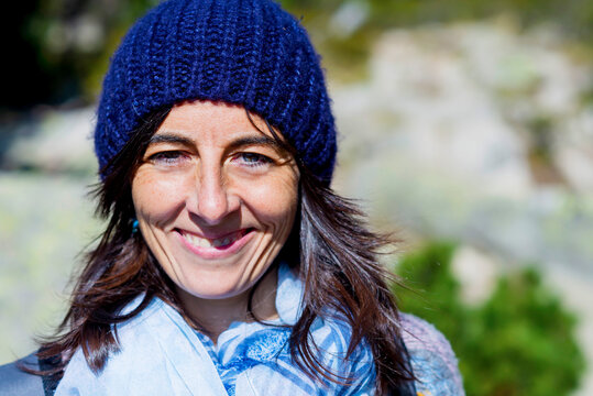 Close-up portrait of smiling female hiker standing in forest during sunny day