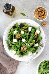 Beetroot salad with feta cheese, arugula and walnuts on a gray background. Top view.