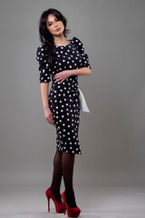 an elegant brunette woman in a dress in the studio