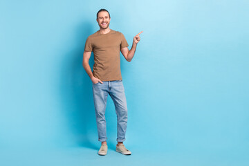 Full length photo of cheerful positive guy dressed beige t-shirt pointing finger empty space...