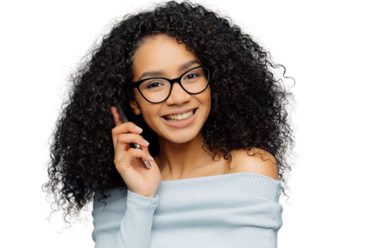 Portrait of satisfied African American woman talks on mobile phone, enjoys nice conversation, tells news to best friends, smiles broadly as hears funny story, isolated over blue background. Technology - Powered by Adobe