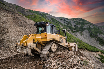 Yellow excavator on new construction site, with the bright sun and nice red sky in the background © suvorovalex