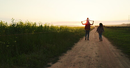 Family walking along a farm at sunset, bonding and having fun in nature. Agriculture, happy family...