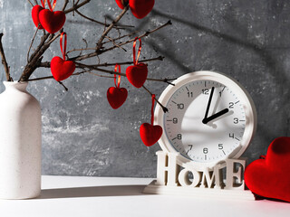 Vase with branches with red hearts and a clock. Concept of love , cosiness, romance, valentine's day. Shades