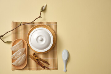 Top view of a white bowl decorated with a dish of edible bird’s nest, ginseng (Panax ginseng) and...