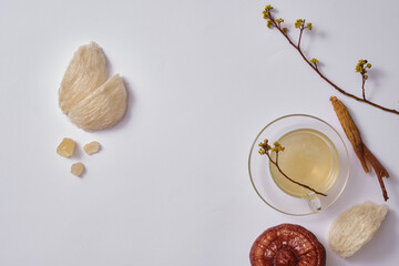 Edible bird’s nest, rock sugar, lingzhi mushroom, ginseng and transparent cup with bird’s nest soup on white background. Blank space for product presentation. Healthcare concept