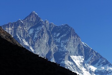 A group of trekkers climbing up to Nangkartshang Peak with Mt. Lhotse, Nepalese Himalayas