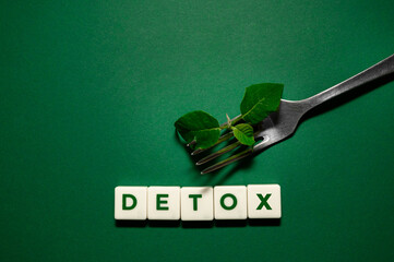the word detox made from letters with a fork and a patch on a green background. Body detoxification and healthy food concept. Detox diet, clean and healthy food