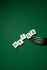 the word detox made from letters with a fork and a patch on a green background. Body detoxification and healthy food concept. Detox diet, clean and healthy food