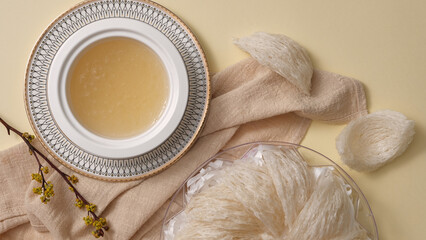 Top view of bowl of bird’s nest soup, raw bird nest and white handkerchief on beige background. Food supplement for the immune system, increase resistance, anti-aging