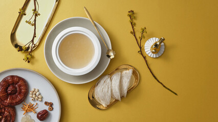A white bowl containing bird’s nest soup arranged with edible bird’s nest and a dish of many...