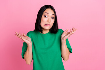 Photo of confused guilty adorable girl with bob hairdo dressed green t-shirt shrugging shoulders isolated on pink color background - obrazy, fototapety, plakaty