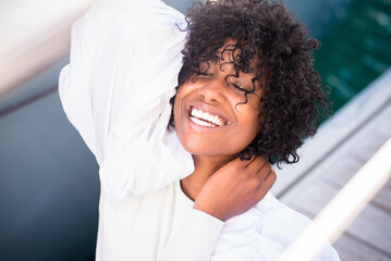 Joyful black afro american young woman laughing a lot having fun alone. Pretty african model ethnic hair style enjoying outdoor leisure activity. Model posing.