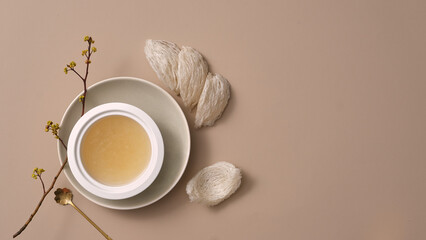 A white porcelain bowl placed on a dish with edible bird’s nest next to it and a spoon with flower branch. Blank space for product promotion. Bird’s nest helps boost immune system