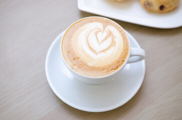 A wooden table with a fragrant cappuccino and baked bread