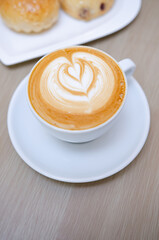 A wooden table with a fragrant cappuccino and baked bread