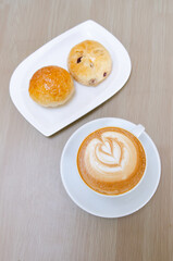 A wooden table with a fragrant cappuccino and baked bread