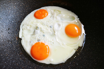 Closeup three of hen eggs being fried in a pan