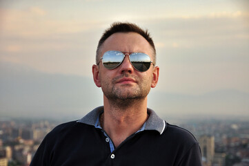Portrait of a man in sunglasses. Man in the background of the city landscape.