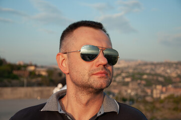 Portrait of a man in sunglasses. Man in the background of the city landscape.