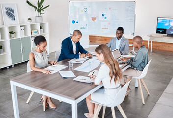 Business people working on documents and laptop at a office boardroom table. Group of professional,...