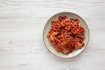 Cooked Greasy Bacon on a Plate on a white wooden background, top view. Space for text.