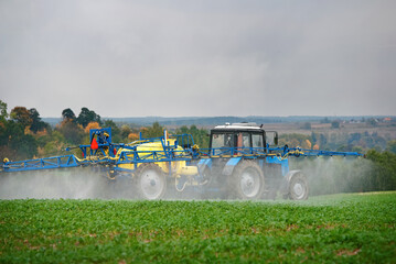 Tractor spraying pesticides on vegetable field with sprayer. Agricultural tractor spraying field....