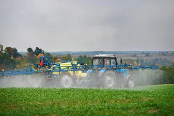 Fotobehang Tractor spraying pesticides on vegetable field with sprayer. Agricultural tractor spraying field. Tractor fertilize field pesticide and insecticide. Tractor with mounted sprayer, farmer crop spraying. © Tricky Shark
