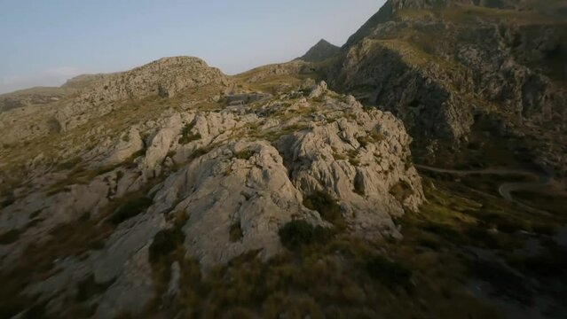 FPV drone forward moving shot over snake road along rocky mountain range in Sa Calobra, Mallorca, Spain during evening time.